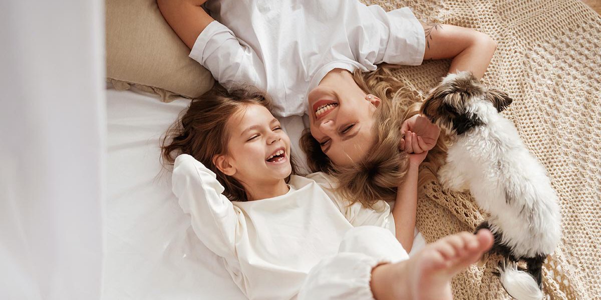 Cute dog is with them. Mother with daughter are at home together