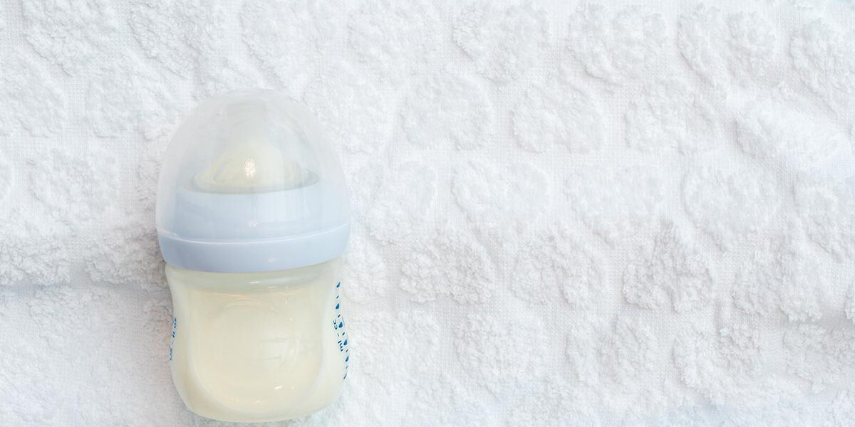 A half-empty bottle of milk nutrition lies on a white towel with copy space