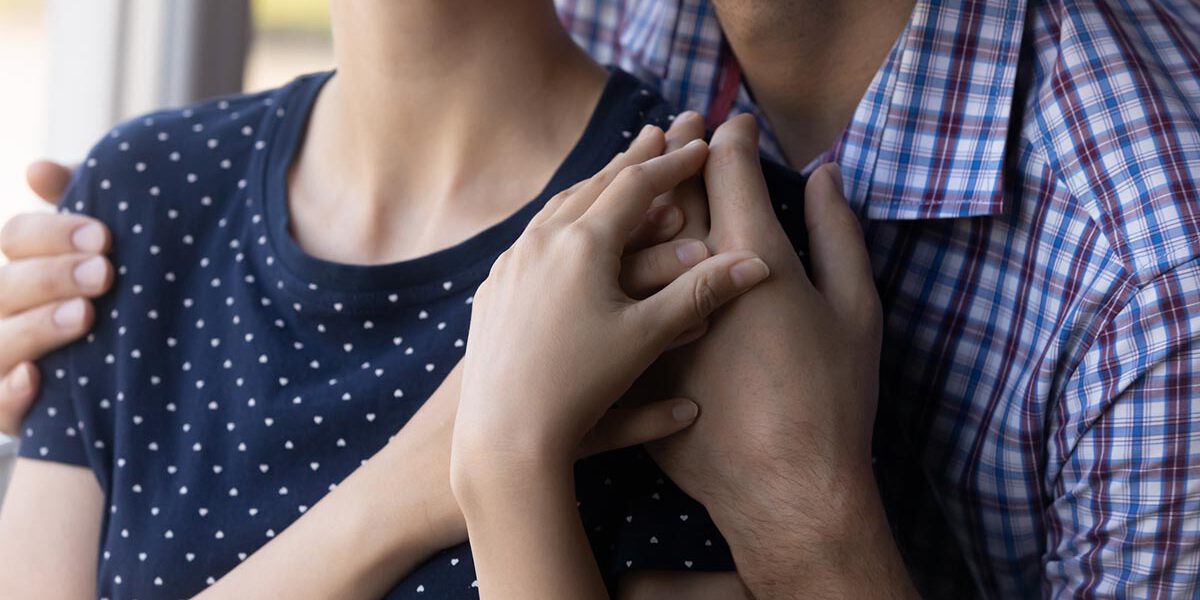 Close up shot of young couple hugging at window