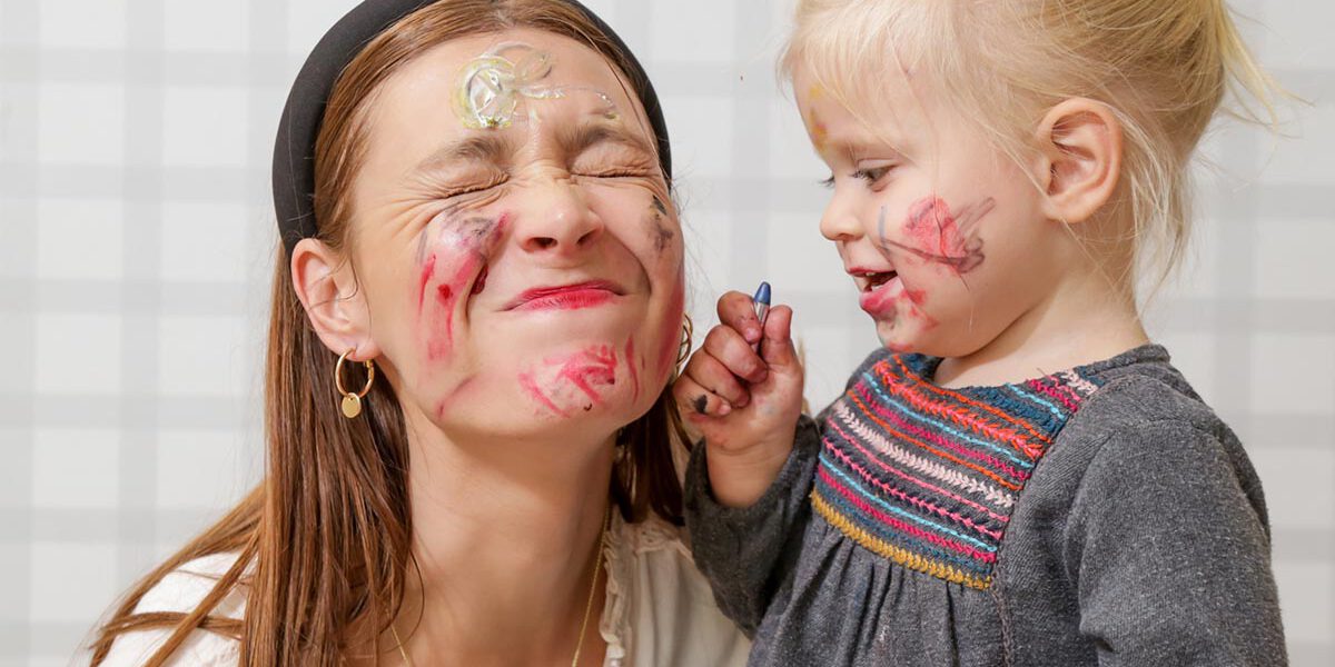 Mom and baby playing with face paint, family time concept