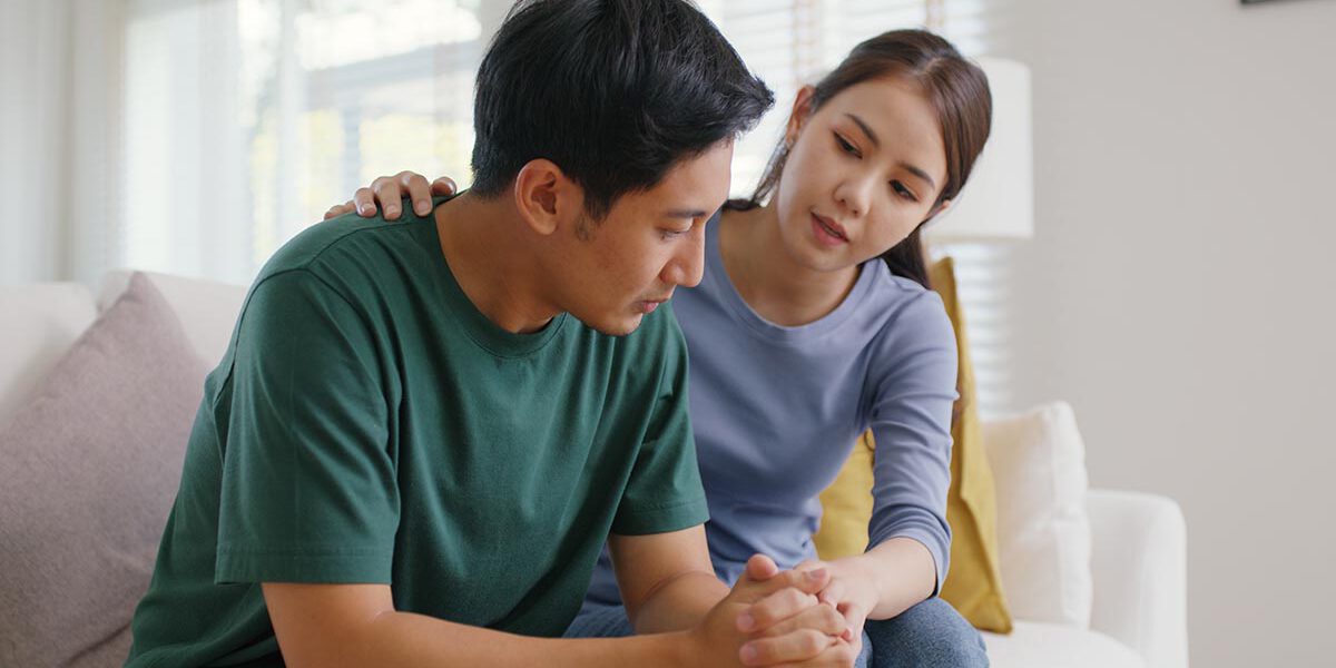 Asia young people stress relief trust talk share suffer cancer pain sick family loss bad news crisis. Sorrow cry man and carer woman sit at sofa home help listen by love hold hand warm hug touch wife.