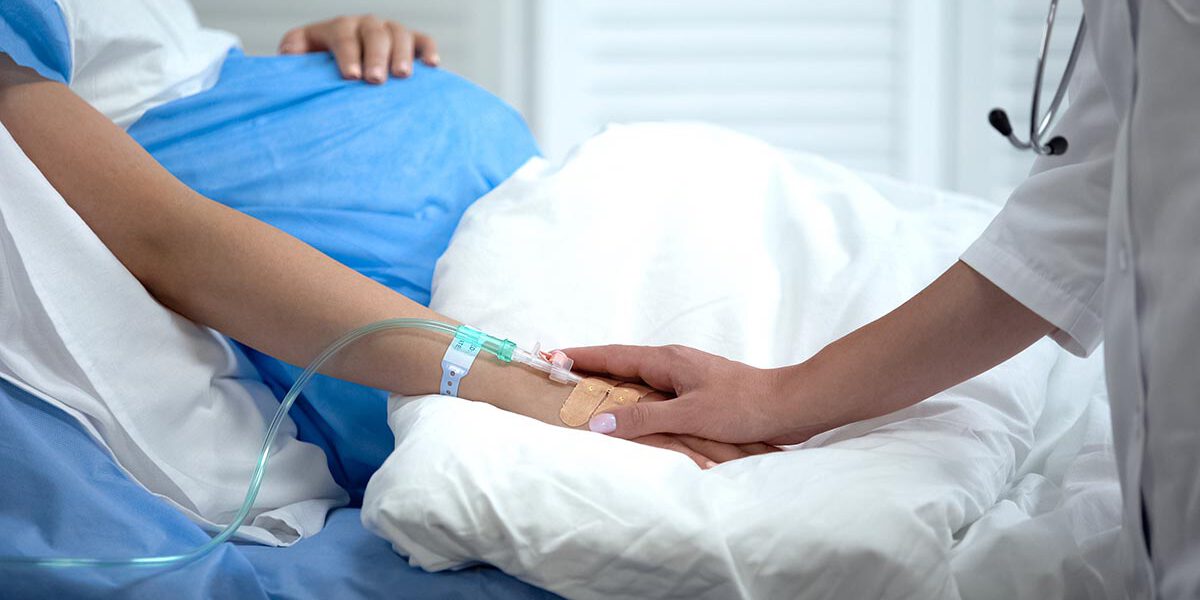 Doctor holding pregnant woman hand with catheter, birth defects prevention