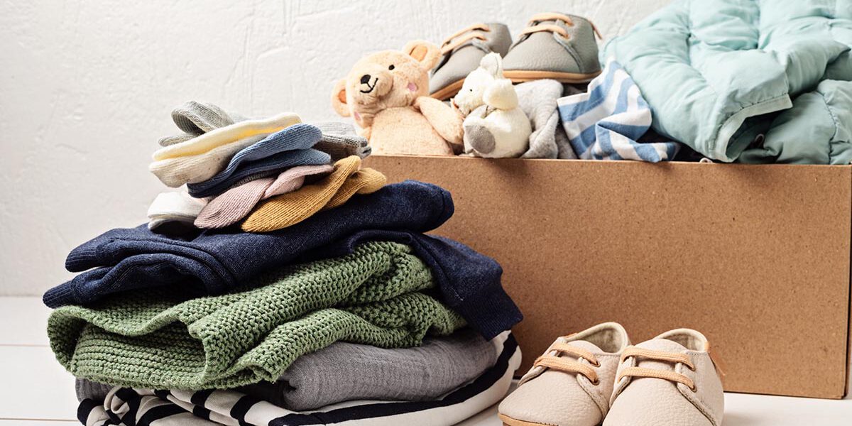 Baby and child clothes, toys in box. Second hand apparel idea. Circular fashion, donation, charity concept