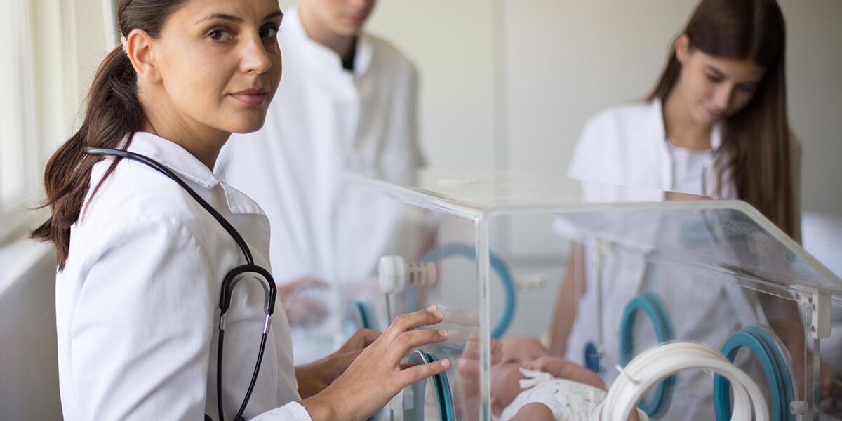Doctor taking care of newborn baby in incubator.